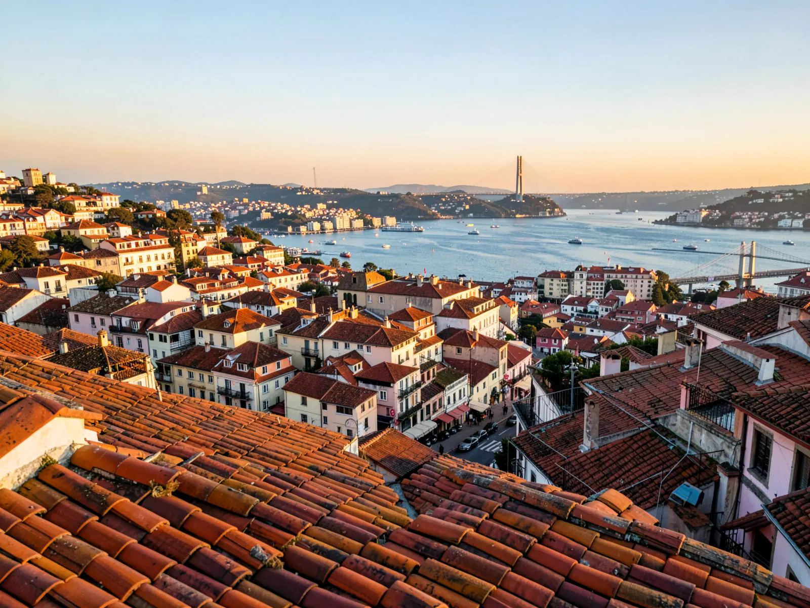 Golden-hour view over the terracotta rooftops of Alfama in Lisbon, Portugal, with the Tagus River behind